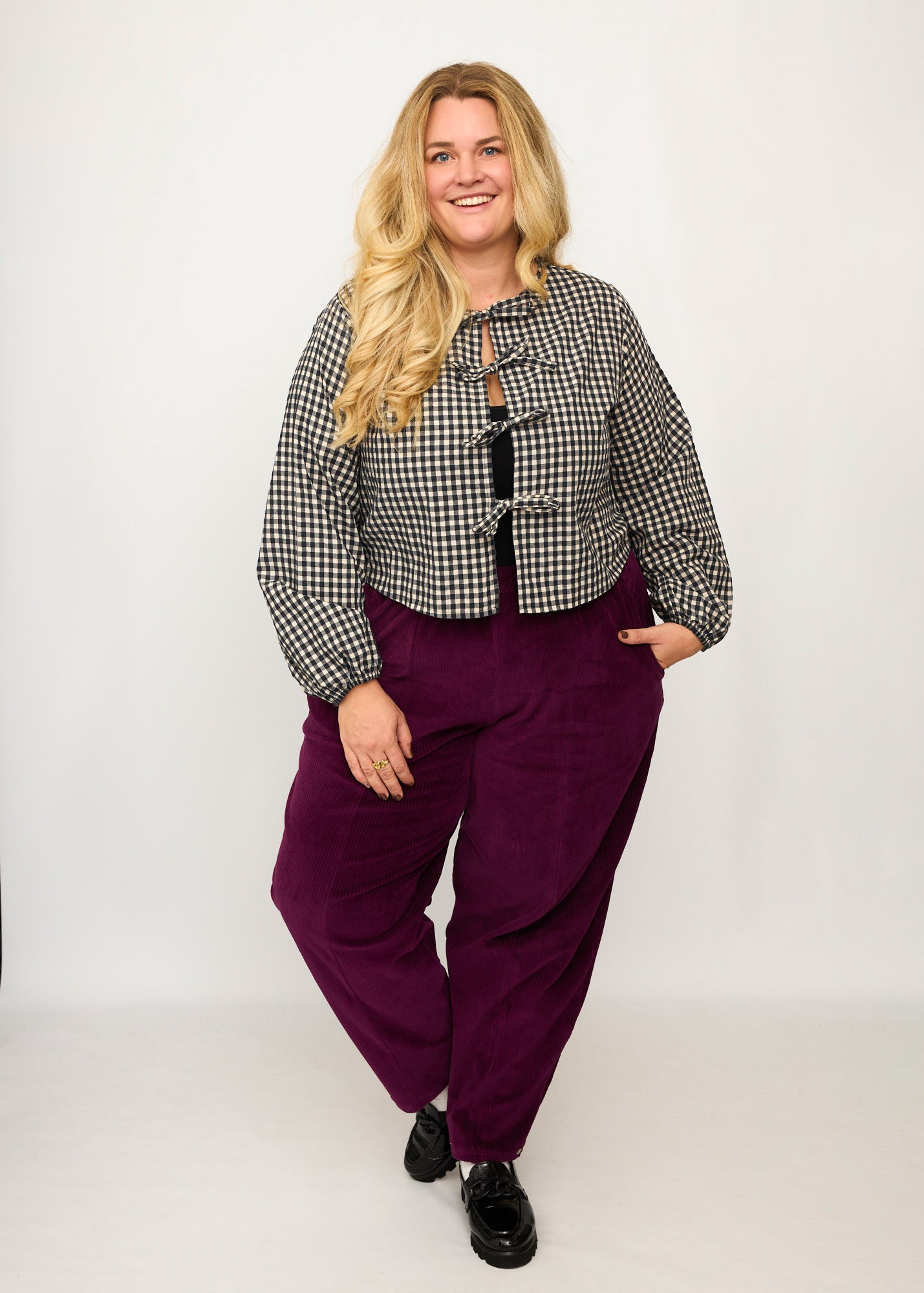 Nina trägt auf dem Foto 'Betty' Größe XXXL, Velvet-Cord aubergine und 'Bella' mit Ballonärmel Größe XXXL, Seersucker schwarz-creme