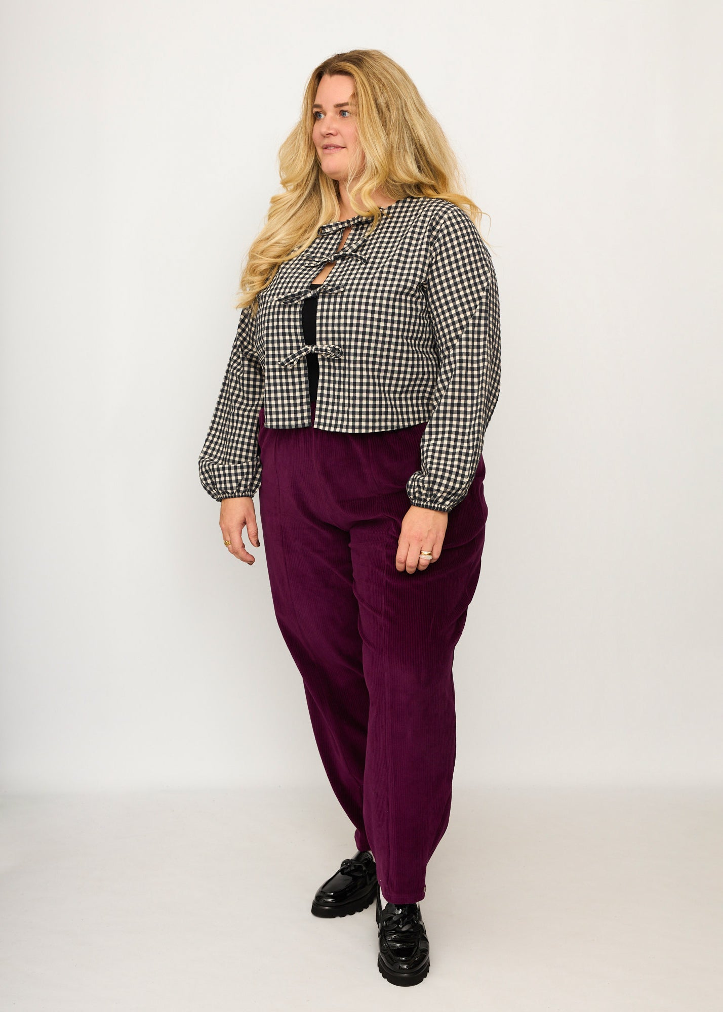 Nina trägt auf dem Foto 'Betty' Größe XXXL, Velvet-Cord aubergine und 'Bella' mit Ballonärmel Größe XXXL, Seersucker schwarz-creme