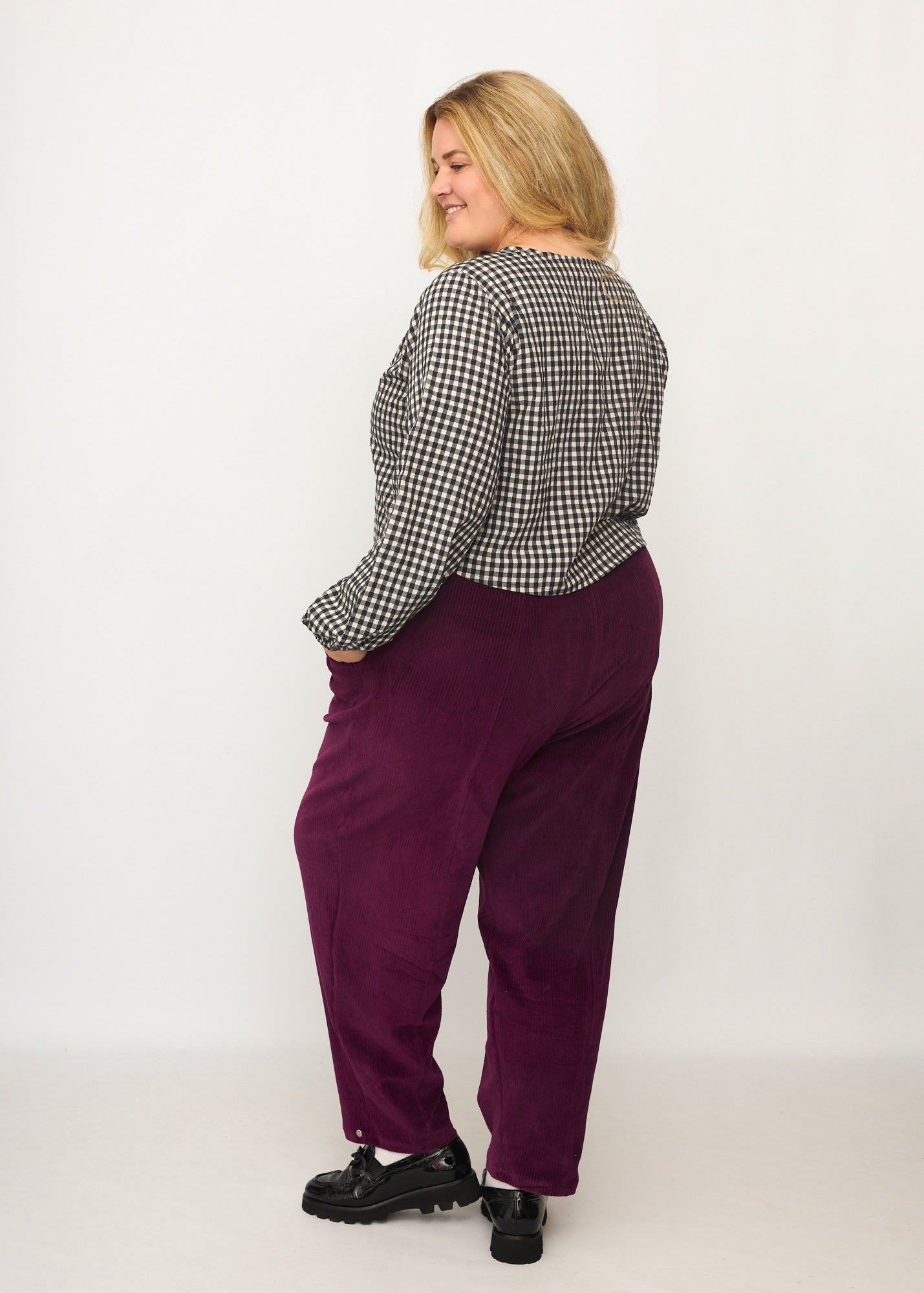 Nina trägt auf dem Foto 'Betty' Größe XXXL, Velvet-Cord aubergine und 'Bella' mit Ballonärmel Größe XXXL, Seersucker schwarz-creme