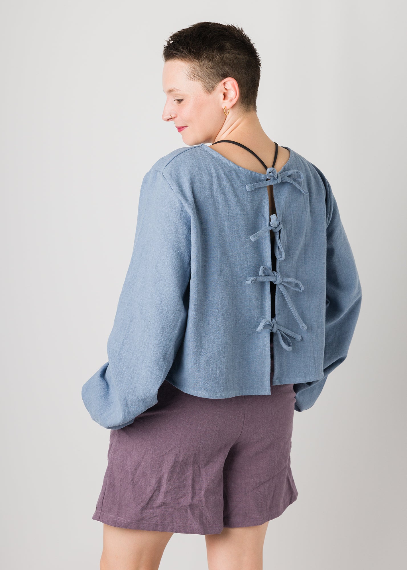 Melly trägt auf dem Foto 'Bella' mit Ballonärmeln Größe XL, Leinen stonewashed hellblau und 'Kira' Größe M, Leinen stonewashed pflaume