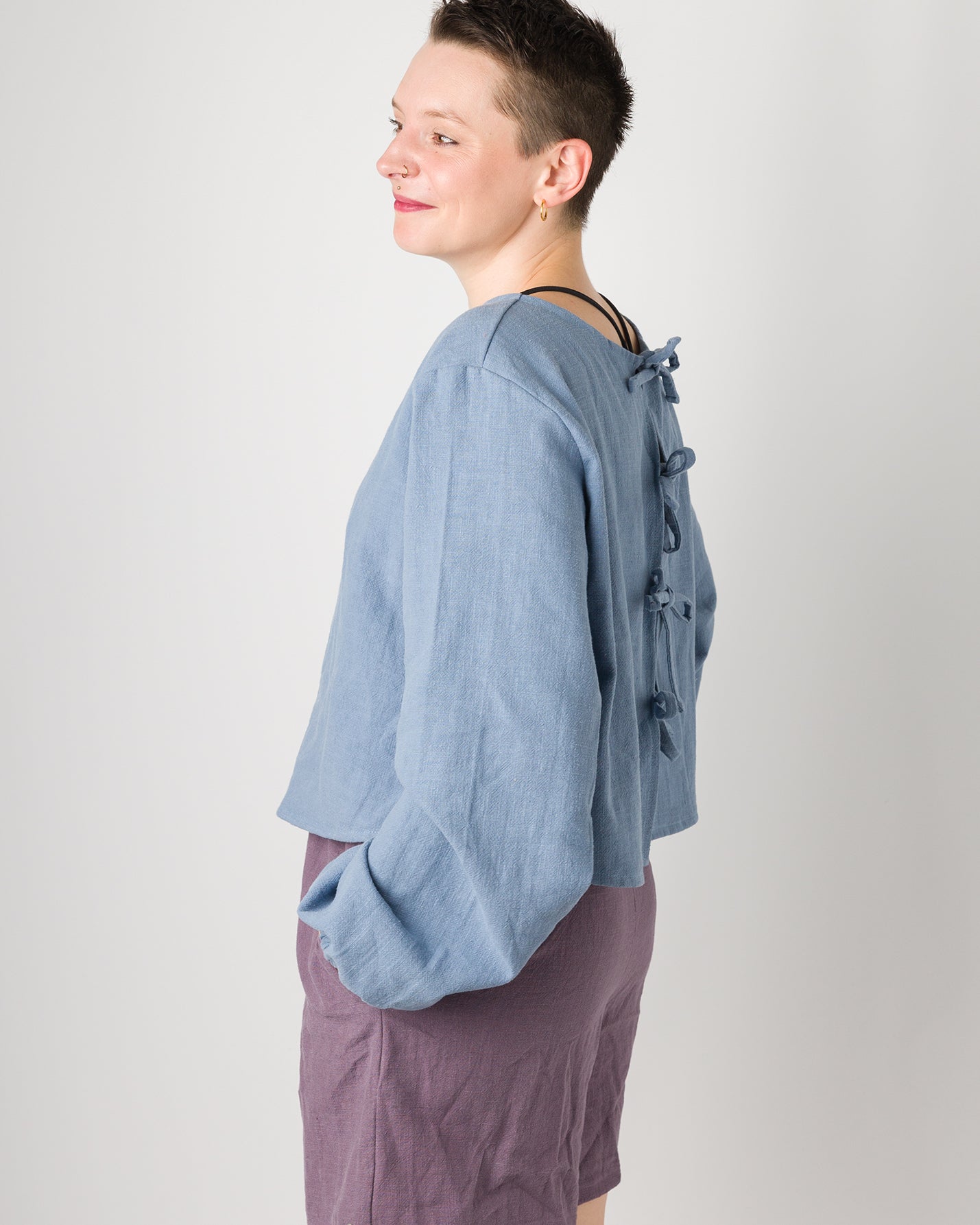 Melly trägt auf dem Foto 'Bella' mit Ballonärmeln Größe XL, Leinen stonewashed hellblau und 'Kira' Größe M, Leinen stonewashed pflaume