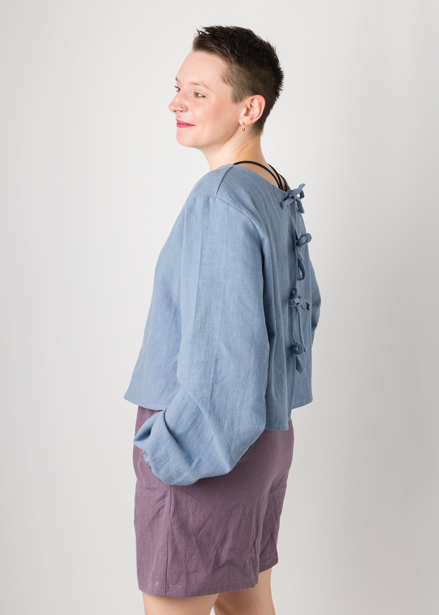 Melly trägt auf dem Foto 'Bella' mit Ballonärmeln Größe XL, Leinen stonewashed hellblau und 'Kira' Größe M, Leinen stonewashed pflaume