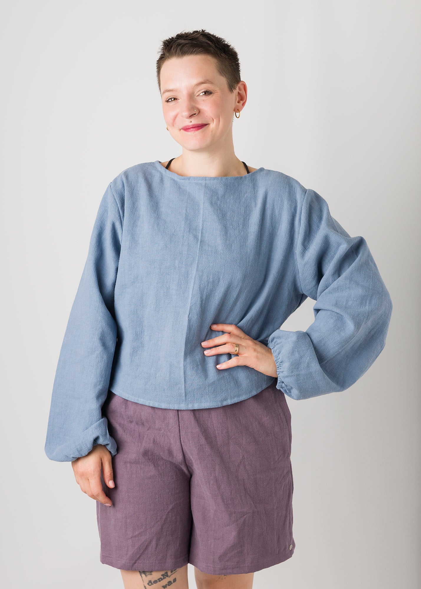 Melly trägt auf dem Foto 'Bella' mit Ballonärmeln Größe XL, Leinen stonewashed hellblau und 'Kira' Größe M, Leinen stonewashed pflaume