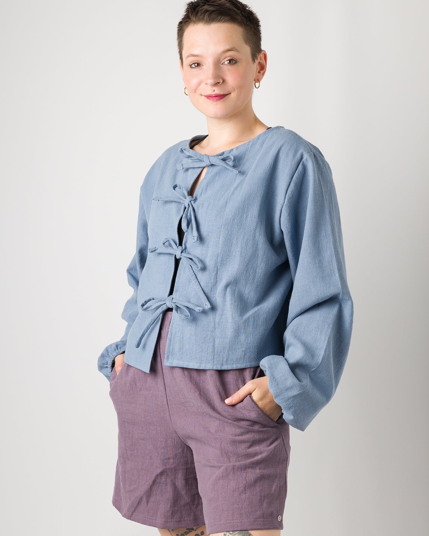 Melly trägt auf dem Foto 'Bella' mit Ballonärmeln Größe XL, Leinen stonewashed hellblau und 'Kira' Größe M, Leinen stonewashed pflaume