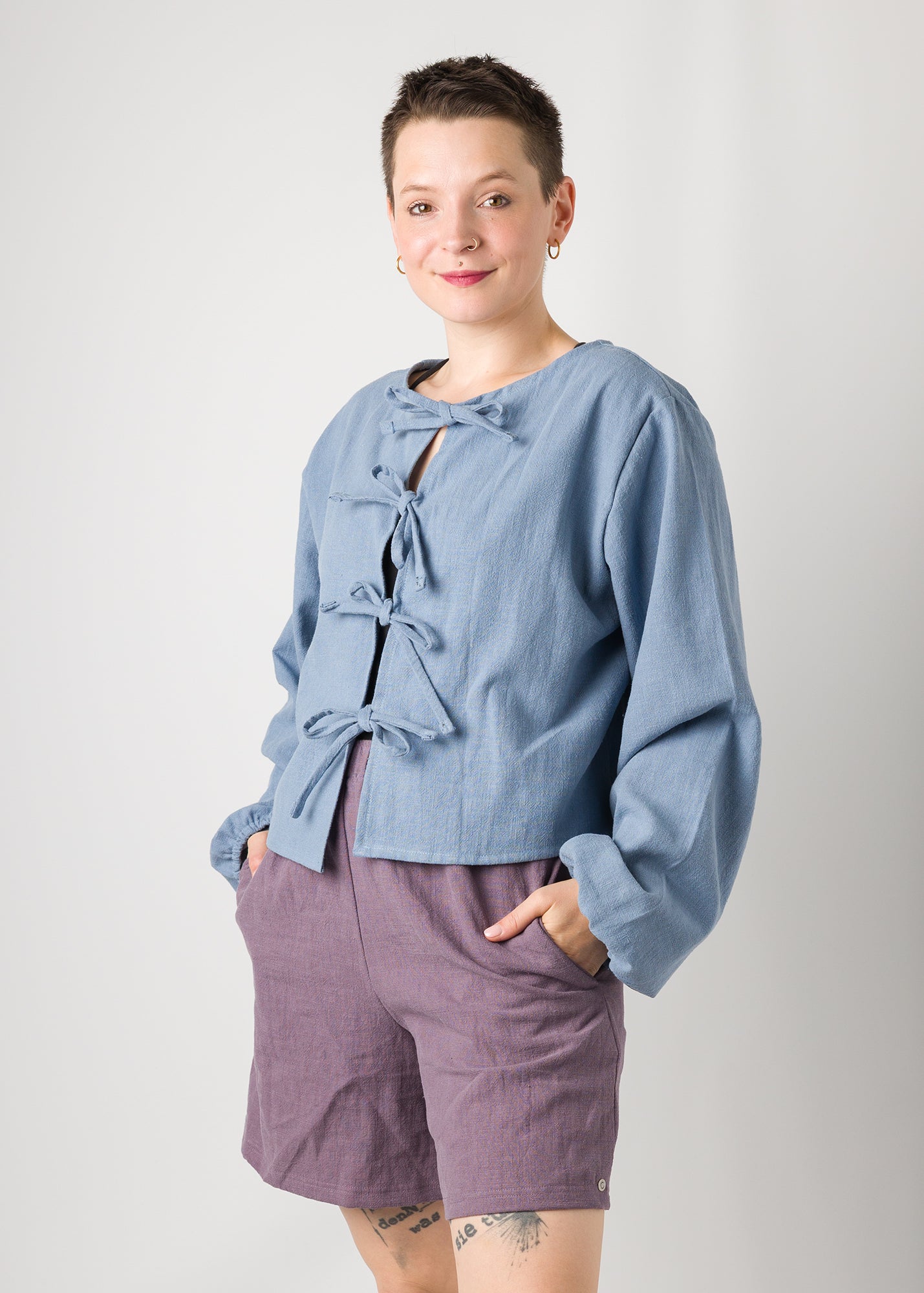 Melly trägt auf dem Foto 'Bella' mit Ballonärmeln Größe XL, Leinen stonewashed hellblau und 'Kira' Größe M, Leinen stonewashed pflaume