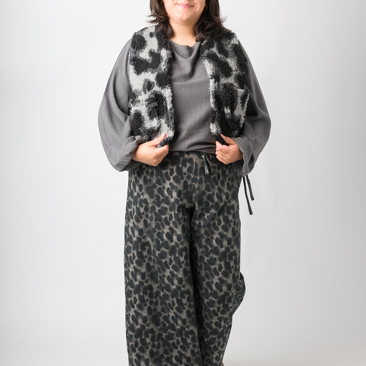 Flores trägt auf dem Foto 'Greta' mit Ballonärmel Größe XL, EcoVeroLeinen grau, 'Waltraut' Größe XXL/XXXL, Plüsch 'Dark Leobert' und 'Holly' weites Bein Größe XXL, Muster elastisch 'Dark Leobert'