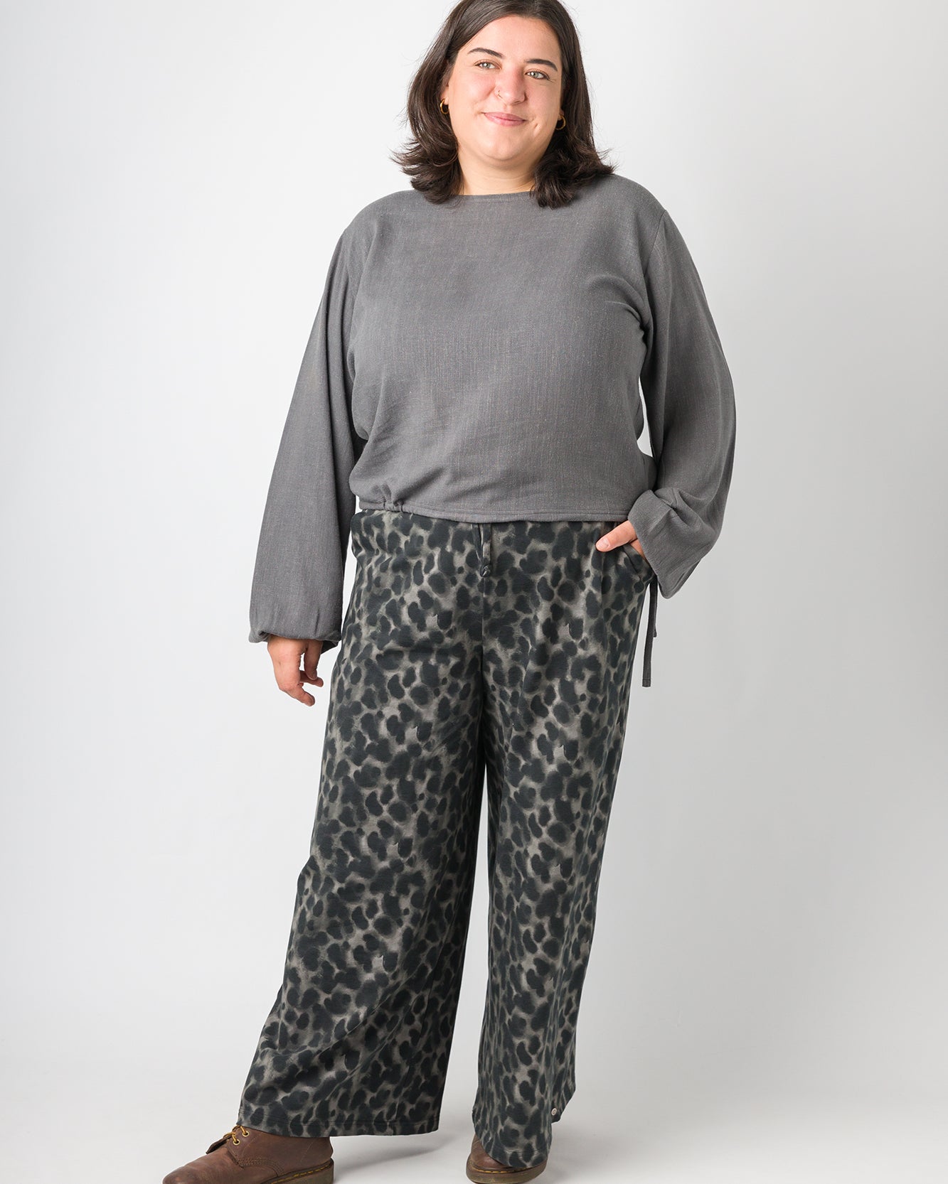 Flores trägt auf dem Foto 'Greta' mit Ballonärmel Größe XL, EcoVeroLeinen grau und 'Holly' weites Bein Größe XXL, Muster elastisch 'Dark Leobert'