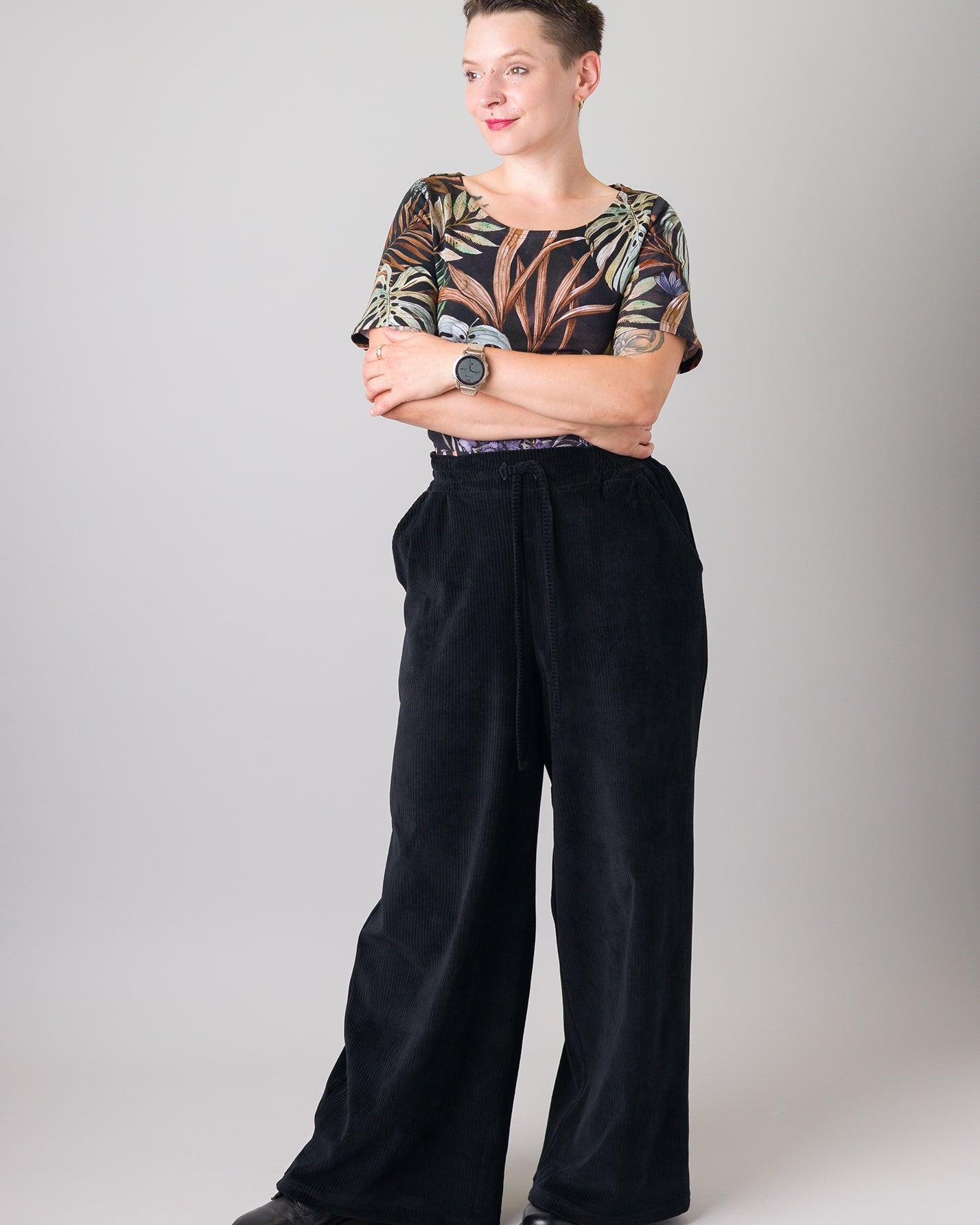 Melly trägt auf dem Foto 'Conni' kurzarm Größe S, Muster elastisch 'Plantlover' und 'Holly' weites Bein Größe XS, Velvet-Cord schwarz