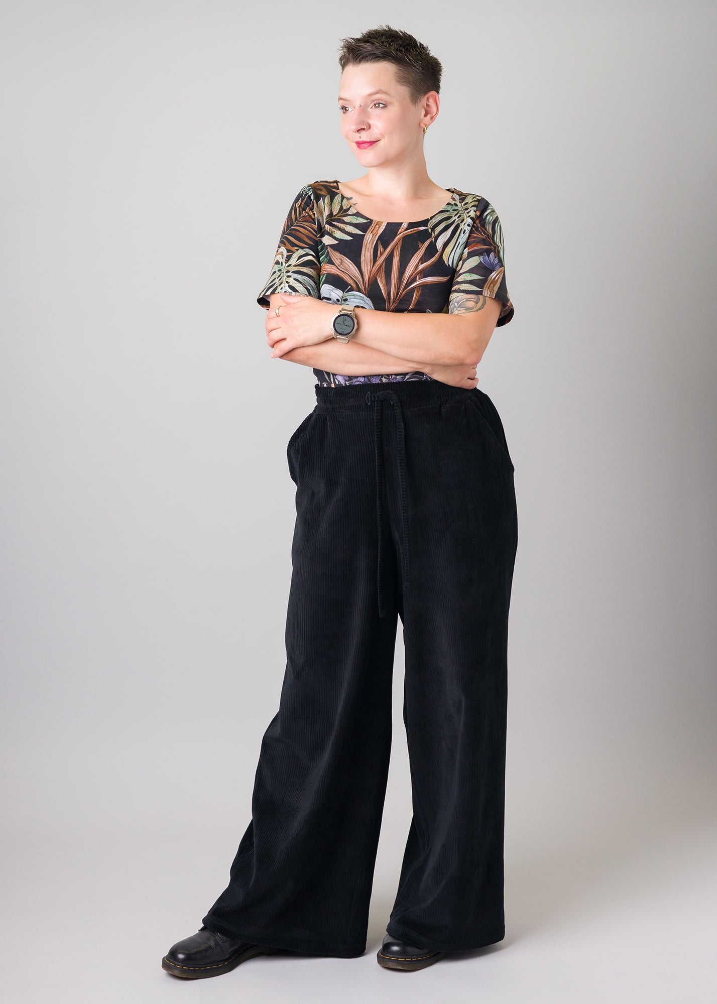 Melly trägt auf dem Foto 'Conni' kurzarm Größe S, Muster elastisch 'Plantlover' und 'Holly' weites Bein Größe XS, Velvet-Cord schwarz