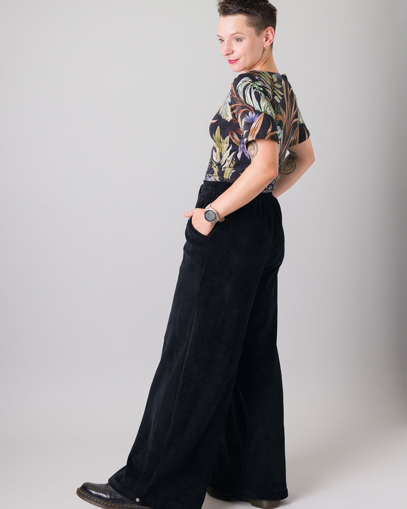 Melly trägt auf dem Foto 'Conni' kurzarm Größe S, Muster elastisch 'Plantlover' und 'Holly' weites Bein Größe XS, Velvet-Cord schwarz