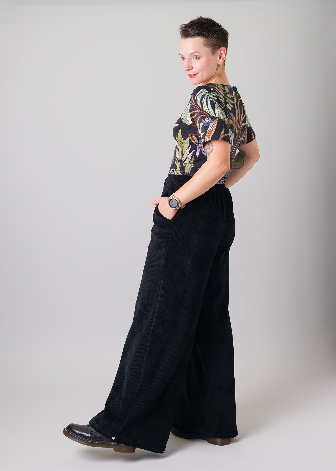 Melly trägt auf dem Foto 'Conni' kurzarm Größe S, Muster elastisch 'Plantlover' und 'Holly' weites Bein Größe XS, Velvet-Cord schwarz