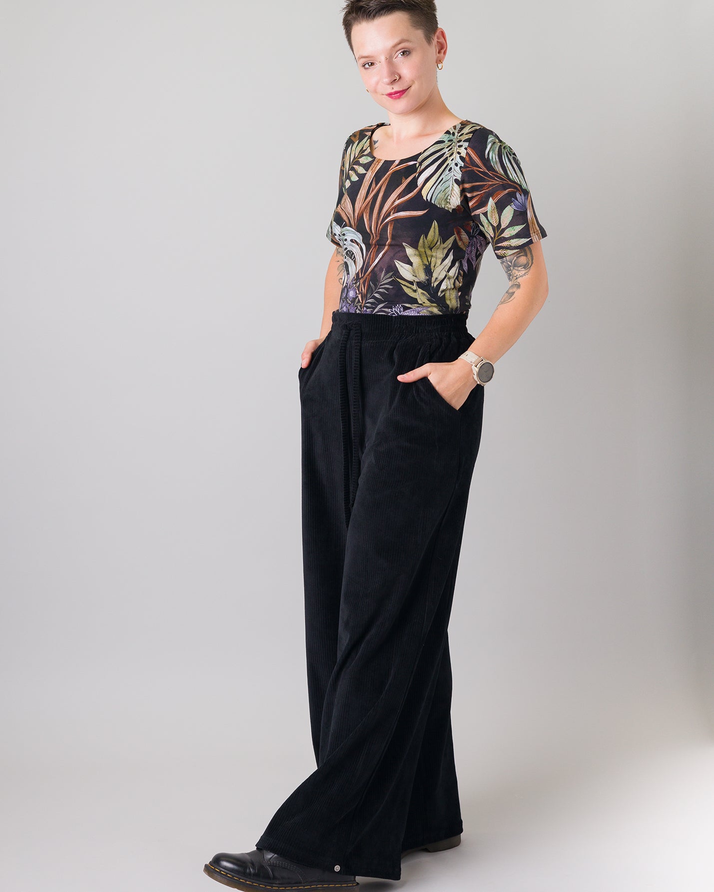 Melly trägt auf dem Foto 'Conni' kurzarm Größe S, Muster elastisch 'Plantlover' und 'Holly' weites Bein Größe XS, Velvet-Cord schwarz