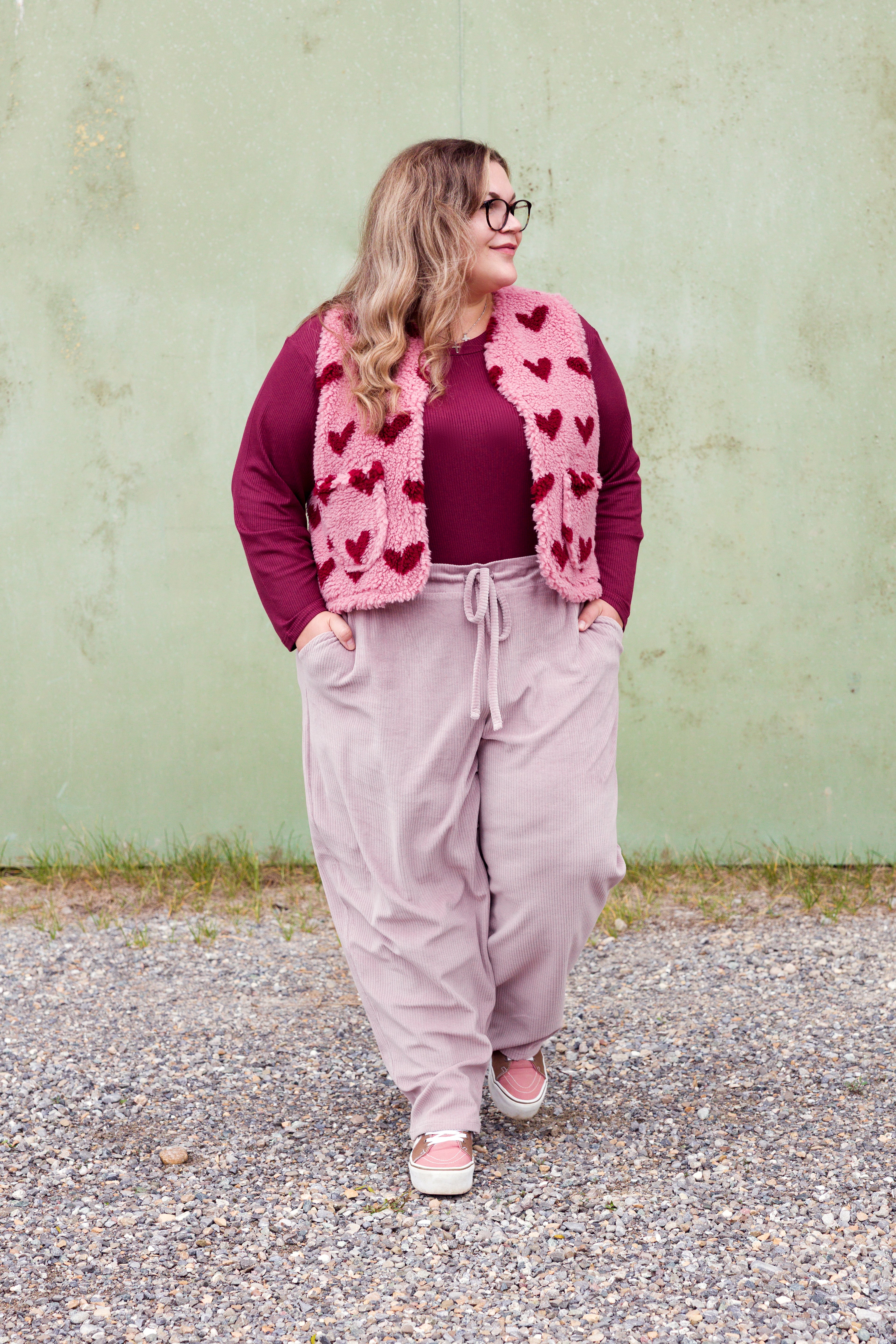 Vroni trägt auf dem Foto 'Theo' Größe 4XL, Rippjersey burgund, 'Waltraut' mit Taschen Größe 4XL/5XL, Muster Plüsch 'Herzchen rosa-rot' und 'Holly' schmales Bein Größe 4XL, Velvet-Cord flieder