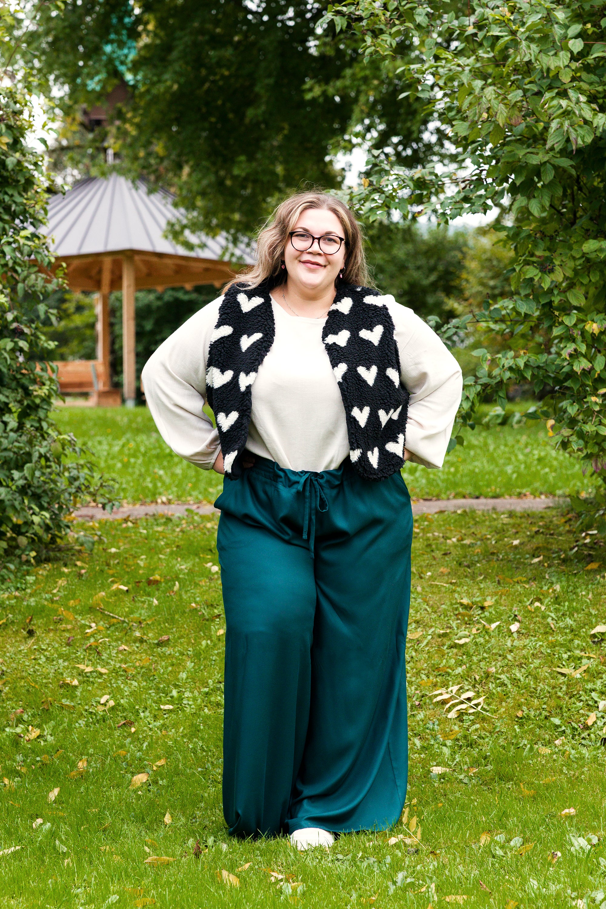 Vroni trägt auf dem Foto 'Greta' Größe 4XL, EcoVero Leinen creme, 'Waltraut' Größe 4XL/5XL, Plüsch Herzchen schwarz-creme und 'Holly' weites Bein Größe 5XL, EcoVeroCrepe flaschengrün