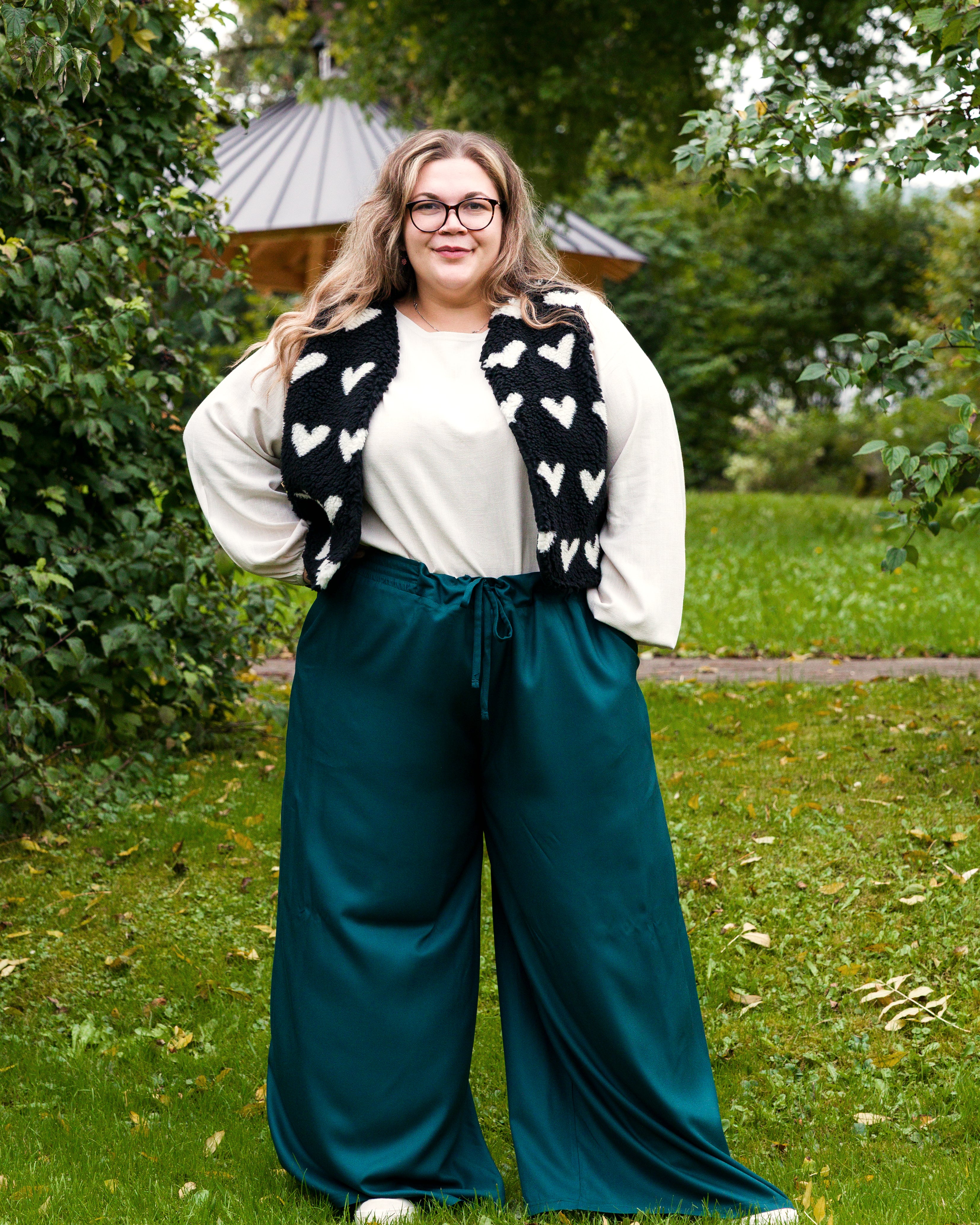 Vroni trägt auf dem Foto 'Greta' Größe 4XL, EcoVero Leinen creme, 'Waltraut' Größe 4XL/5XL, Plüsch Herzchen schwarz-creme und 'Holly' weites Bein Größe 5XL, EcoVeroCrepe flaschengrün