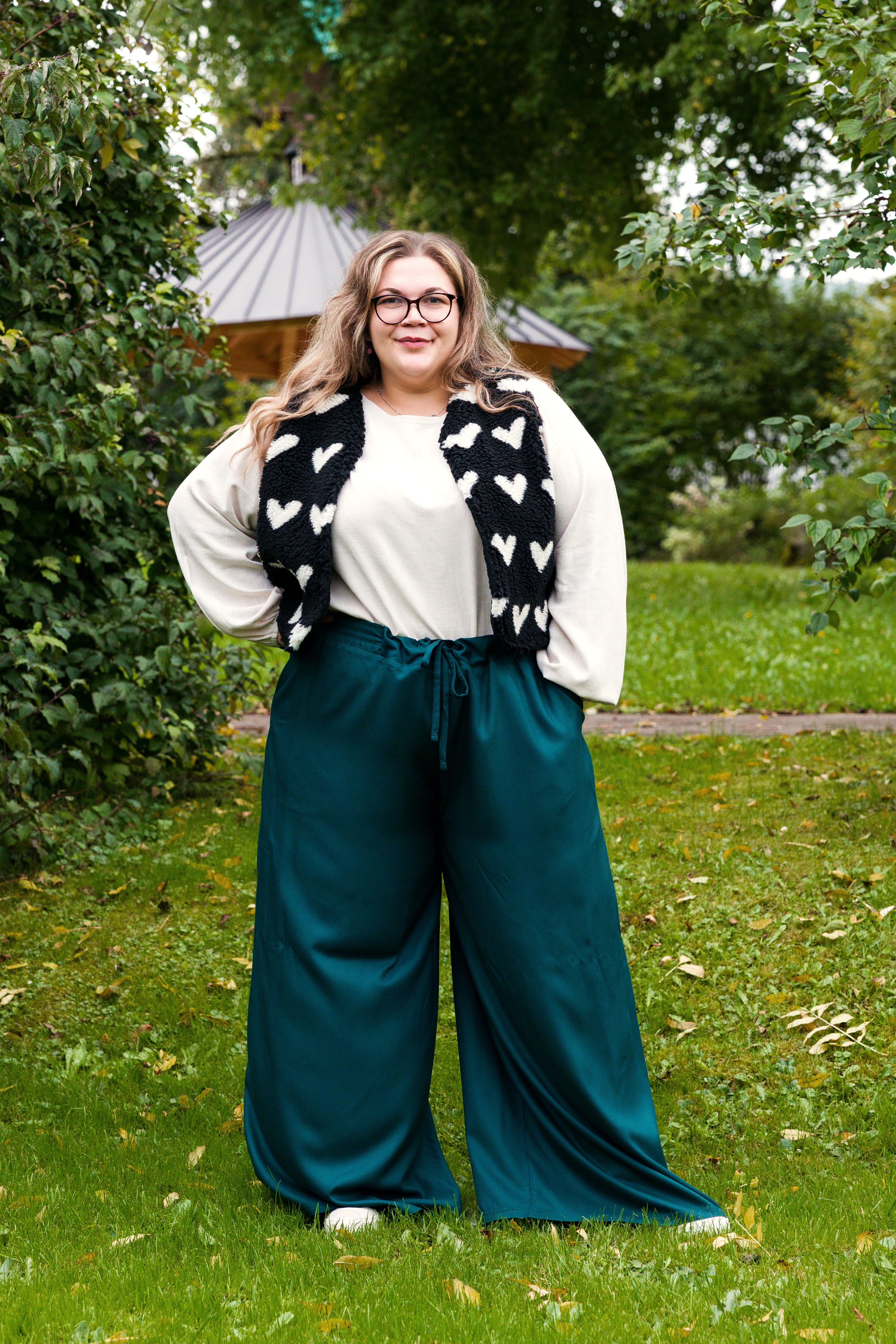 Vroni trägt auf dem Foto 'Greta' Größe 4XL, EcoVero Leinen creme, 'Waltraut' Größe 4XL/5XL, Plüsch Herzchen schwarz-creme und 'Holly' weites Bein Größe 5XL, EcoVeroCrepe flaschengrün