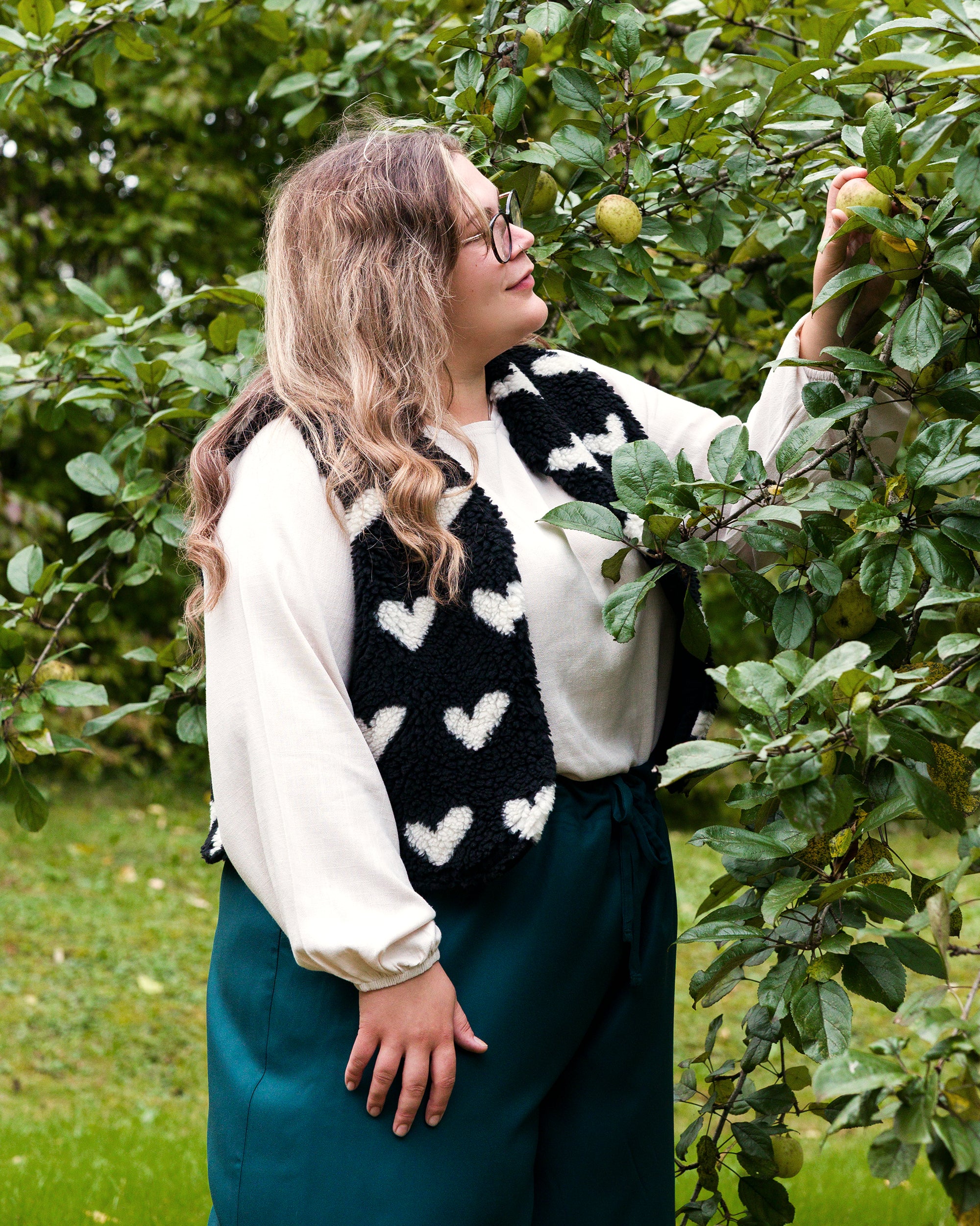 Vroni trägt auf dem Foto 'Greta' Größe 4XL, EcoVero Leinen creme, 'Waltraut' Größe 4XL/5XL, Plüsch Herzchen schwarz-creme und 'Holly' weites Bein Größe 5XL, EcoVeroCrepe flaschengrün