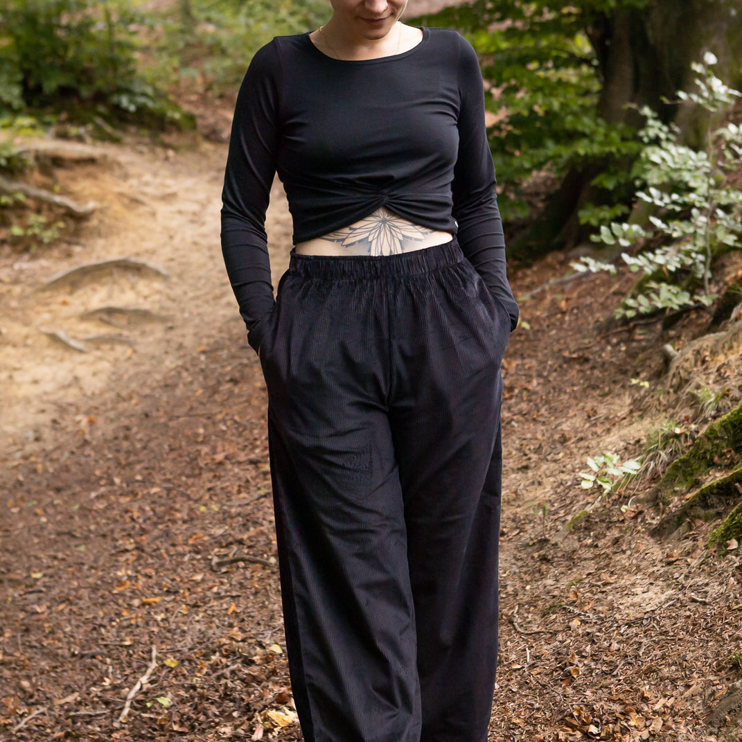 Melly trägt auf dem Foto 'Marlene' Größe M, Cord schwarz und 'Clara' Größe M, Rippjersey schwarz