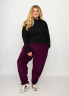 Nina trägt auf dem Foto 'Betty' Größe XXXL, Velvet-Cord aubergine und 'Rosalie' Größe XXXL, Rippjersey schwarz