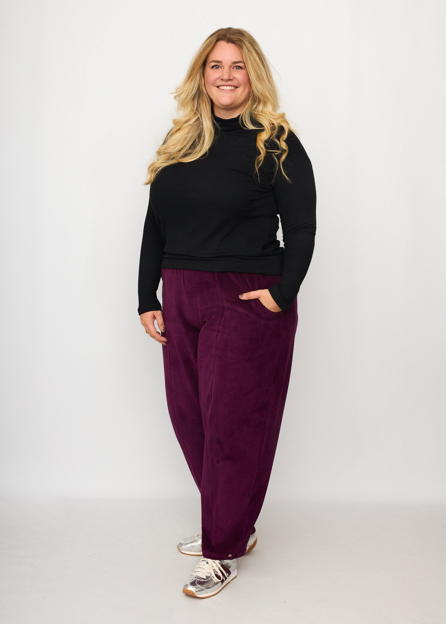 Nina trägt auf dem Foto 'Betty' Größe XXXL, Velvet-Cord aubergine und 'Rosalie' Größe XXXL, Rippjersey schwarz