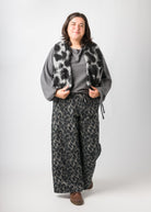 Flores trägt auf dem Foto 'Greta' Größe XL, EcoVeroLeinen grau, 'Holly' Größe XXL, Muster elastisch Dark Leobert und 'Waltraut' Größe XXL/XXL, Plüsch Dark Leobert