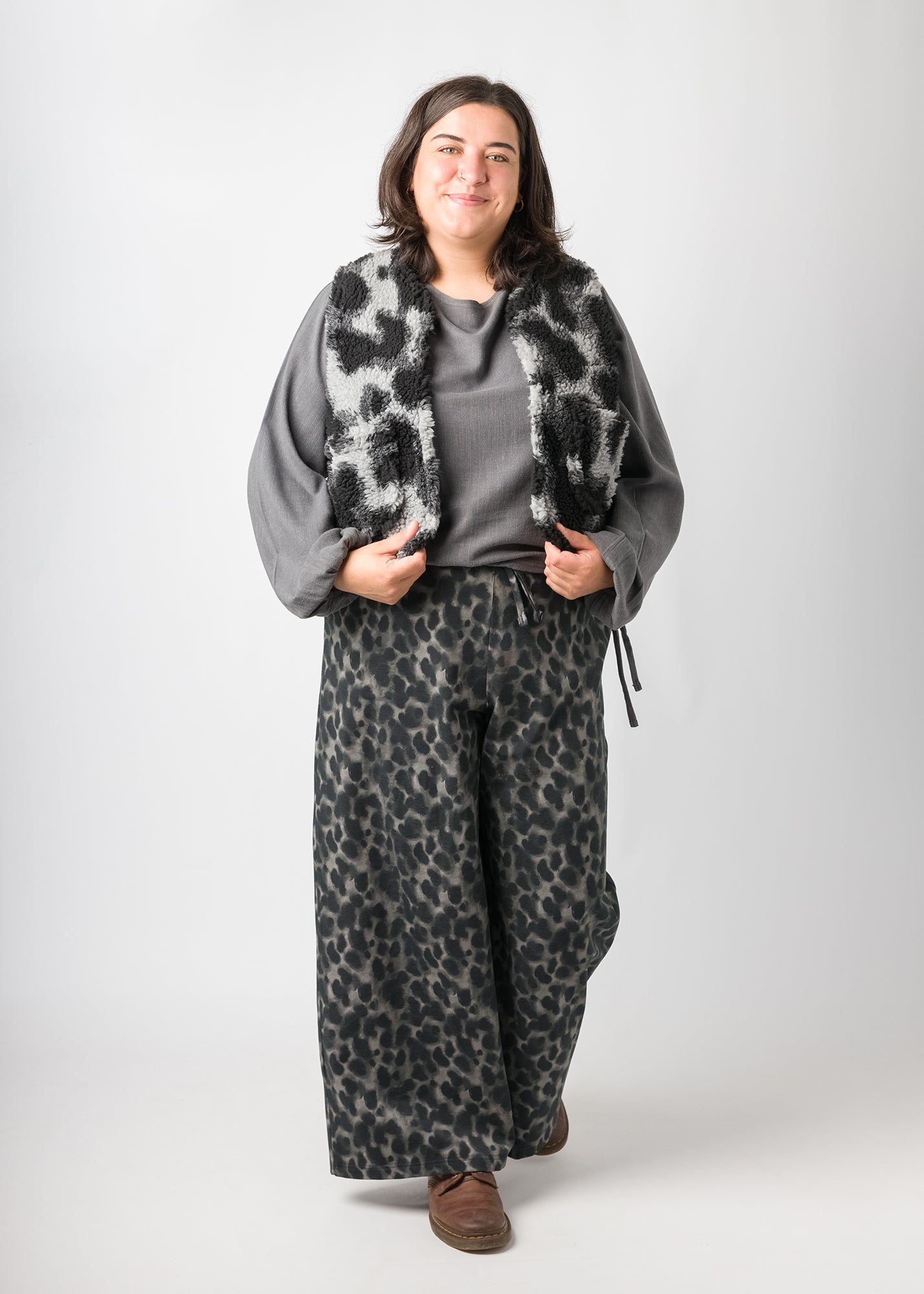 Flores trägt auf dem Foto 'Greta' mit Ballonärmel Größe XL, EcoVeroLeinen grau, 'Waltraut' Größe XXL/XXXL, Plüsch 'Dark Leobert' und 'Holly' weites Bein Größe XXL, Muster elastisch 'Dark Leobert'